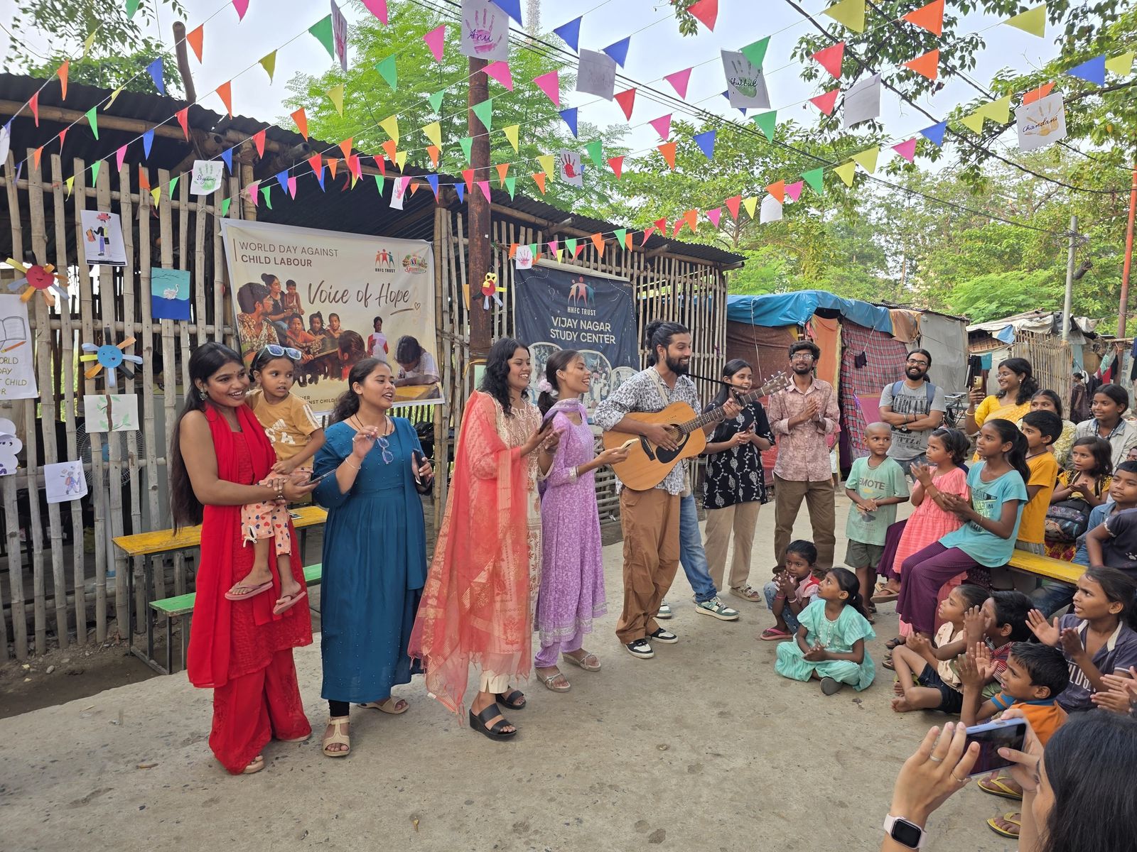 A community cultural gathering with festive bunting and families watching a performance